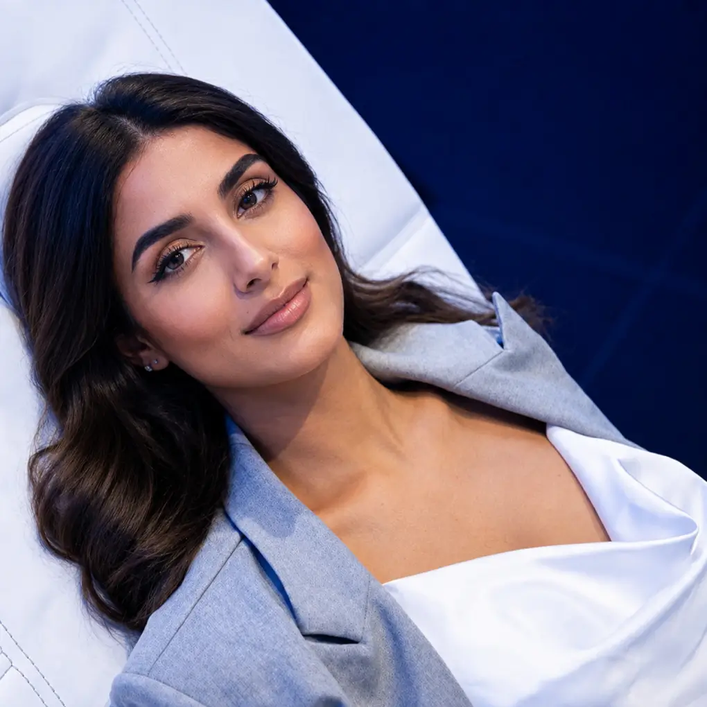 A woman reclining on a white lounge chair at a wellness suite.