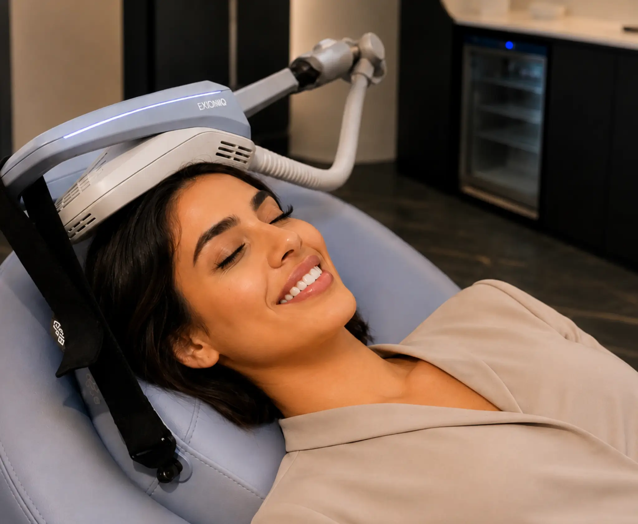 A woman reclining and smiling during a high-tech scalp treatment session.
