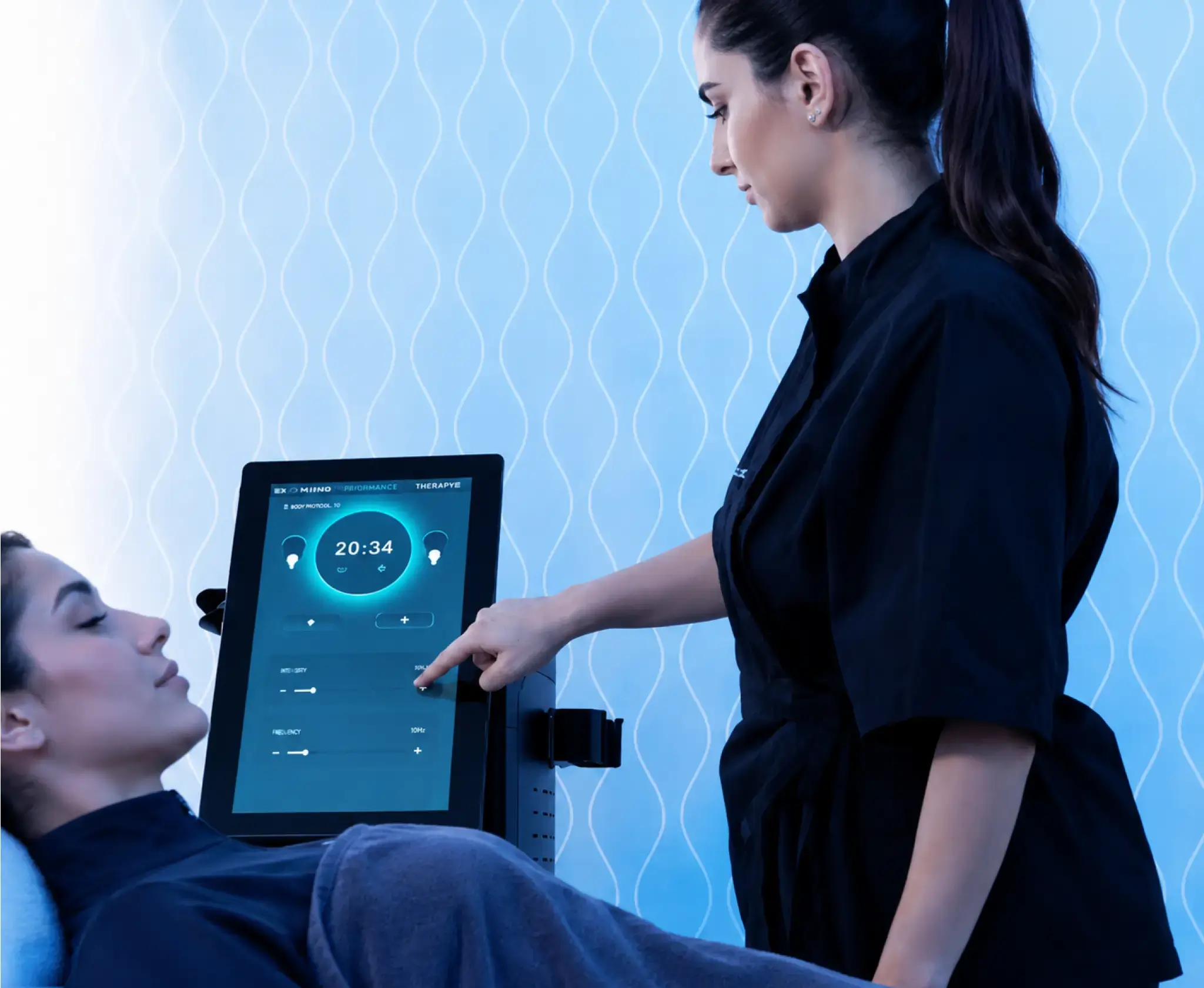A therapist using a touchscreen control panel to administer an advanced body treatment to a client.