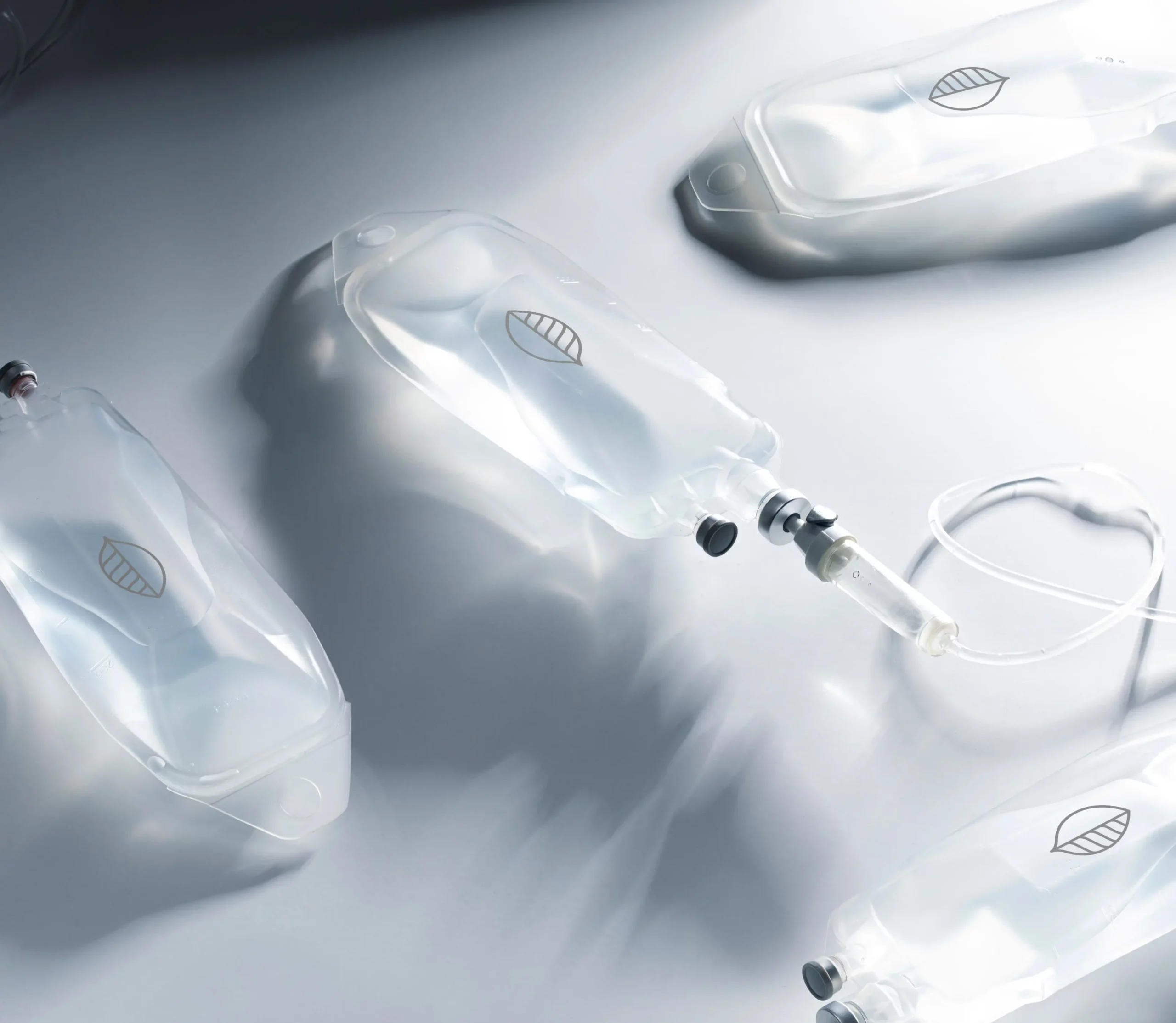 Multiple clear intravenous (IV) drip bags and tubing laid out on a clean, modern surface.
